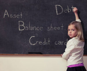 Little girl writing financial terms on the board