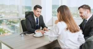 A couple in an office sitting at a desk with a lender explaining a personal loan.