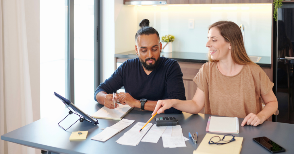 A Couple sit at a table with document, going over their budget and expenses.