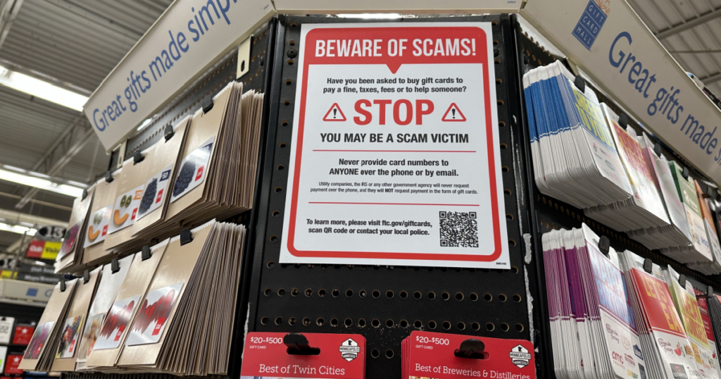 A kiosk of gift cards with a sign warning consumers about scams.