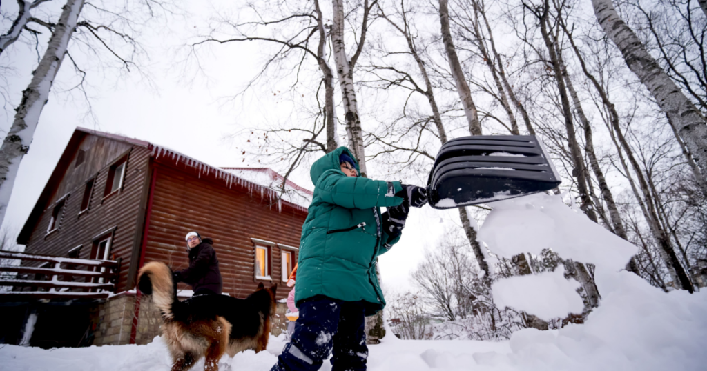 kid shoveling heavy snow with a dog