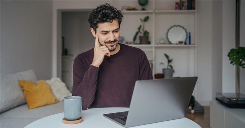 A man in a brown sweater looking at his computer